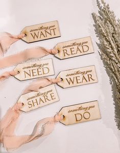 four wooden tags with sayings on them sitting next to some dried grass and a plant