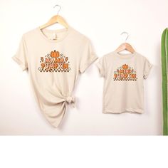 "This Mommy and Me Mama Pumpkin and Mini Pumpkin T-Shirt set is perfect for fall festivities! The t-shirts feature a cute pumpkin design, with \"Mama Pumpkin\" on the adult shirt and \"Mini Pumpkin\" on the child's shirt. Made from comfortable, breathable material, these shirts are great for family outings or cozy nights in. The set is available in various sizes to ensure a perfect fit for both mother and child. Show off your love of autumn with these adorable matching shirts! Key features: - Cute pumpkin design - \"Mama\" on adult shirt - \"Mini\" on child's shirt - Comfortable material - Available in various sizes How to order: 1. Select  Color 2. Select Size/Style 3. Add to Cart 4. If looking to purchase multiple sizes/colors repeat steps 1-3  5. Proceed to Check Out Please take a look Family Letter Print Tops For Fall, Casual Family T-shirt For Fall, Fall Tops With Letter Print, Fall Family Outfits, Sweatshirts Cute, Fall Festivities, Family Outings, Matching Sweatshirts, Mini Pumpkins