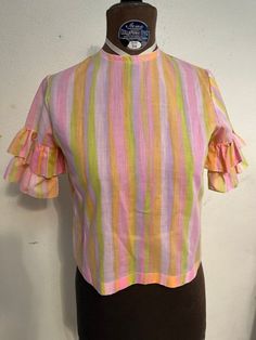 "Vintage 1960s pink pastel striped blouse.  Button back, double ruffle on sleeves. Buttons up the back. Nice vintage condition, but does have a small and subtle smattering of tiny stains (haven't tried to clean). Being sold as is Women's small Semi sheer cotton 34\" bust 18.75\" shoulder to hem 13\" back shoulders" Pink Cotton Blouse With Flutter Sleeves, Striped Short Sleeve Blouse With Ruffles, Pink Fitted Blouse With Flutter Sleeves, Retro Pink Ruffled Top, Retro Pink Top With Ruffles, Fitted Striped Blouse With Ruffles, Pink Retro Cotton Blouse, Pink Cotton Retro Blouse, Red Velvet Shirt