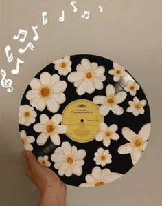 a hand holding up a record with flowers on it and the words written in white