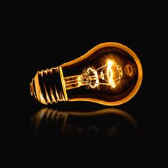 a light bulb that is turned on in the dark, with its bright yellow glow