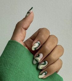 a woman's hand with green and white manicures holding onto a green sweater