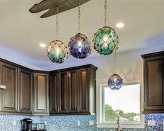 a kitchen with brown cabinets and blue glass tile backsplash, lights hanging from the ceiling