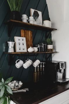 a kitchen with green walls and shelves filled with coffee cups, teapots and other items