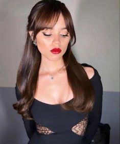 a woman with long brown hair wearing a black dress and red lipstick is posing for the camera