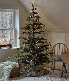 a decorated christmas tree in the corner of a room next to a chair and window