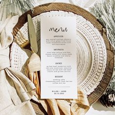 a plate with a menu on it next to napkins and silverware, along with pine cones