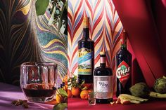 three bottles of alcohol sitting on top of a table next to some vegetables and fruit