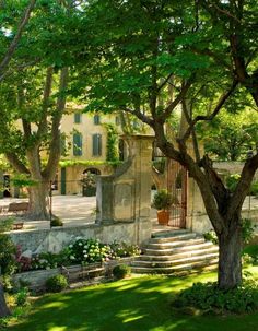 an outdoor area with steps and trees in the shade, surrounded by grass and flowers