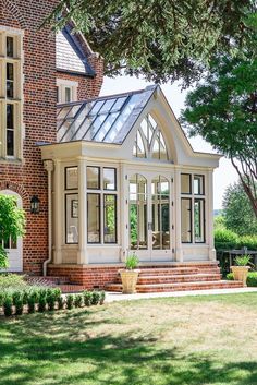 a large brick house with an orangery and white trim on the front door is shown