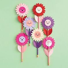 colorful paper flowers with faces on them are arranged in a row against a green background