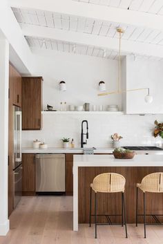 a kitchen with two stools in front of the counter and an island that has three chairs on it