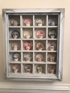 a white frame filled with lots of different types of plates on display in it's shadow box