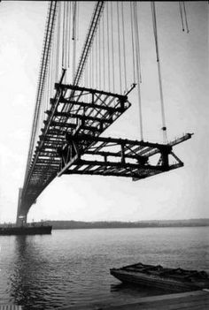 a boat is floating in the water under a bridge that's being lifted by crane chains