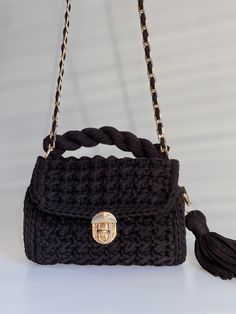 a black handbag with a gold lock on the front and tasselled handles