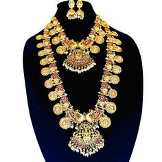 Product Description: Enhance your traditional attire with this Exquisite Indian Temple Jewelry Set, meticulously crafted to reflect the rich heritage and elegance of Indian culture. This stunning set features a grand gold-plated necklace adorned with intricate circular motifs, beautifully accented with sparkling red and green stones. At the heart of this masterpiece lies a majestic Lakshmi pendant, symbolizing prosperity and divine blessings, flanked by detailed peacock designs that embody grace and beauty. This set includes a matching pair of earrings, completing the look with timeless elegance. Ideal for brides, this jewelry set is perfect for weddings, religious ceremonies, and festive celebrations. The luxurious gold tones and detailed craftsmanship make it a standout addition to any j Luxury Elegant Temple Necklace, Luxury Elegant Temple Necklace For Festivals, Luxury Temple Pendant Jewelry, Luxury Festive Temple Jewelry Sets, Festive Luxury Temple Necklace, Luxury Temple Jewelry Necklace With Peacock Design, Luxury Temple Necklace With Peacock Design, Luxury Temple Jewelry With Matching Earrings, Luxury Temple Necklace With Peacock Design For Festivals