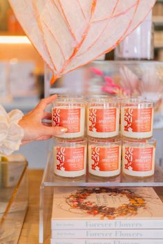 a person is holding up candles in front of a stack of books on a table