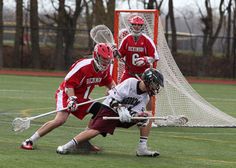 two lacrosse players in red and white uniforms are playing on the field with each other