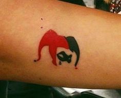 a woman's arm with a red and black joker tattoo on the left side