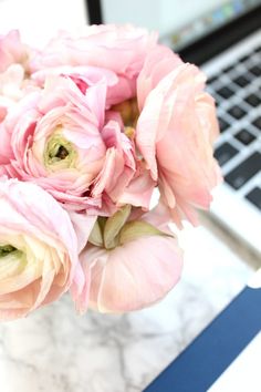 a bouquet of pink flowers sitting in front of a laptop