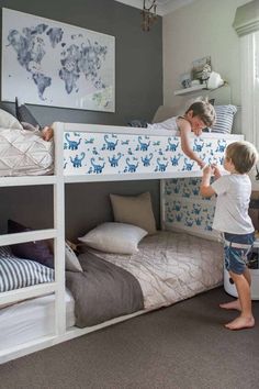 a woman standing next to a child on top of a bunk bed in a bedroom