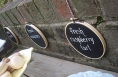 three signs hanging from the side of a brick wall that say fresh raspberry tart