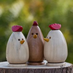 three wooden chickens sitting on top of a tree stump