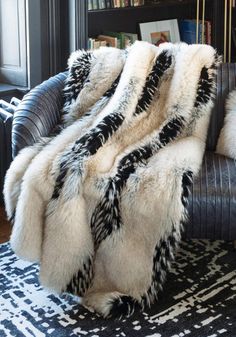 Aaaaaaahhhhhh - that's you, at the end of a long, stress-filled day, relaxing under an Ivory Fox throw. New in our Limited Edition Collection of faux fur throws, you'll love the lure of this warm, dramatic fur that works in many room settings.  A trifecta of color, texture and toning, Ivory Fox is an exciting combination of warm Ivory and pale Taupe with Ebony highlights and subtle tipping. Believably beautiful and amazingly authentic, guard hairs add to the authenticity of this extravagantly luxurious cruelty-free replica. At home in both contemporary and transitional settings, the luxe, lush vibe belies the fact that Ivory Fox throws are amazingly practical! Though luxuriously lined in velvet, Ivory Fox throws are meant to be used and enjoyed, thanks to the convenience of machine wash/li Fur Rugs Living Room, Fur Rug Living Room, Moody Room, Mom Cave, Lodge Ideas, Fur Rugs, Modern Lodge, Romantic Bedroom Decor, Denim Jacket With Fur