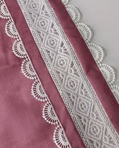 two pieces of white lace on pink fabric