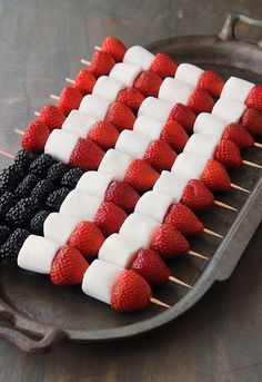 strawberries and blackberries are arranged on skewers in the shape of an american flag