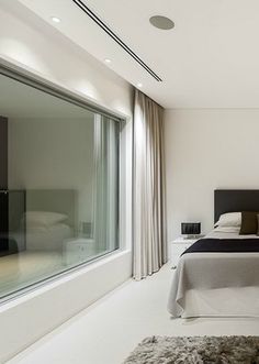 a bedroom with a large bed next to a window and rugs on the floor