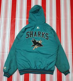 a green jacket with sharks on it sitting on top of a red and white striped sheet