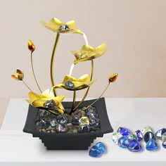 a vase filled with yellow flowers sitting on top of a table next to some stones