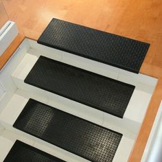 three black and white floor mats sitting on top of a wooden floor next to a heater