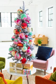 a brightly colored christmas tree in the middle of a living room with colorful furniture and pillows