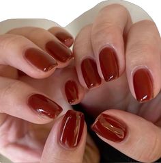 a woman's hands with red manies holding onto her nail polish in the shape of a heart