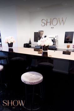 a black counter with three stools in front of it and flowers on the table