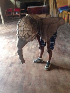 a man is holding something in the shape of a horse's head while standing on a hard wood floor