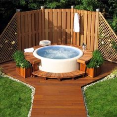 a hot tub in the middle of a wooden decked area surrounded by greenery