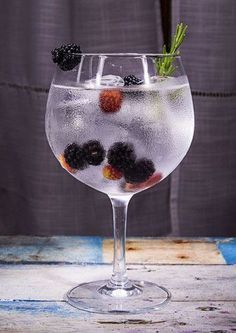 a wine glass filled with water and berries