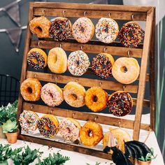 a wooden rack filled with lots of doughnuts on top of a white table