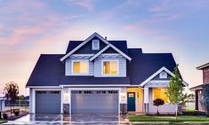 a large house with two garages in front of it at sunset or sunrise time