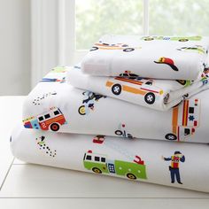 a stack of white sheets with colorful firetrucks and trucks printed on them