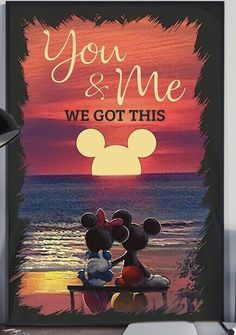 a mickey and minnie mouse poster sitting on top of a desk next to a lamp