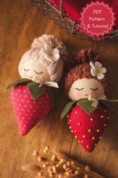 two little dolls sitting on top of a wooden table next to strawberries and flowers