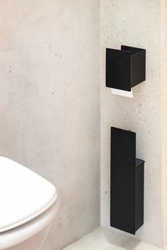 two black square holders on the wall next to a toilet