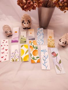 there are many cards on the table next to a vase full of flowers and two sheep figurines