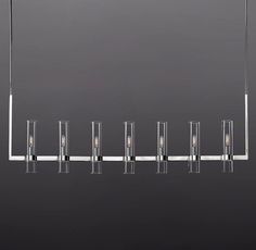 a long rectangular light fixture hanging from the ceiling with five lights on each end and four poles attached to it