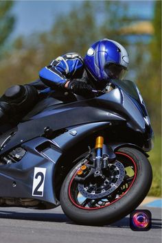 a man riding on the back of a motorcycle down a race track with his helmet on