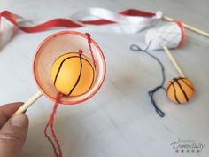 a hand is holding a basketball lollipop on a stick with two other lollipops in the background